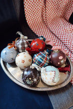 Load image into Gallery viewer, Decorative Christmas ornaments on a silver tray with a patterned fabric background