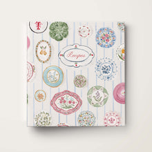 Load image into Gallery viewer, Recipe book with decorative cover featuring watercolor illustrations of china plate on a white background.